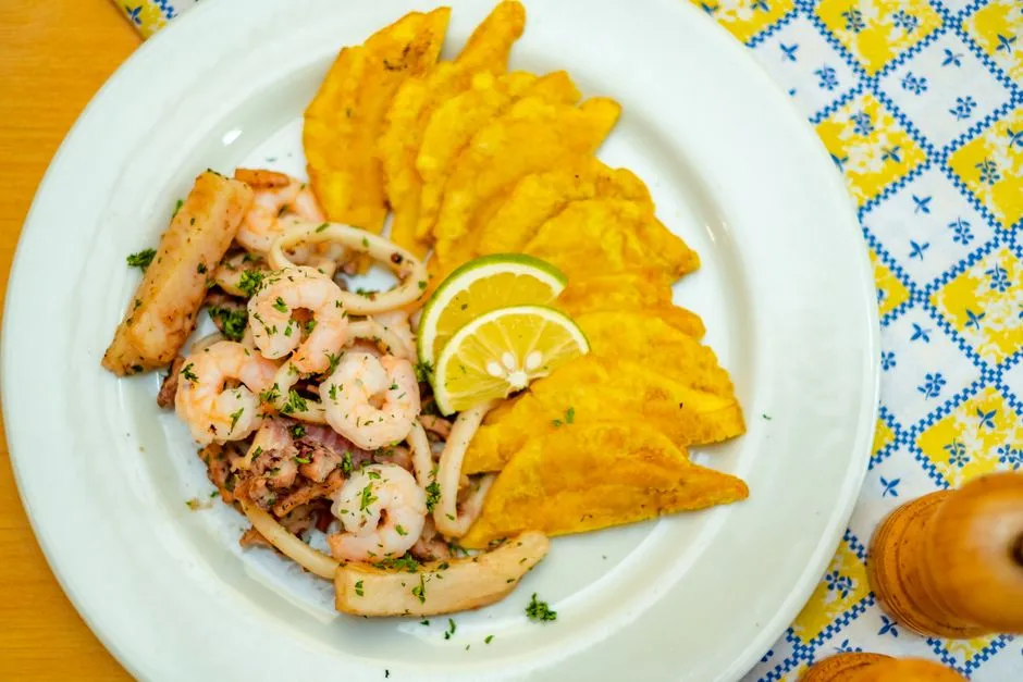 Assiette de fruits de mer créoles : crevettes et calmars sautés, bananes plantain frites et tranches de citron vert