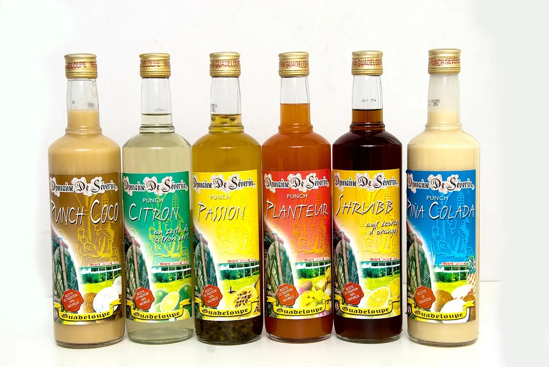 Gamme de punchs et rhums arrangés guadeloupéens de la distillerie Séverin alignés pour la dégustation : coco, citron, passion, planteur, shrubb et piña colada