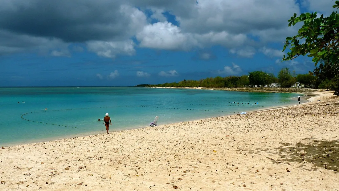 Plage de la Guadeloupe à Port-Louis avec lagon turquoise et ciel chargé de nuages sombres typique de la saison cyclonique