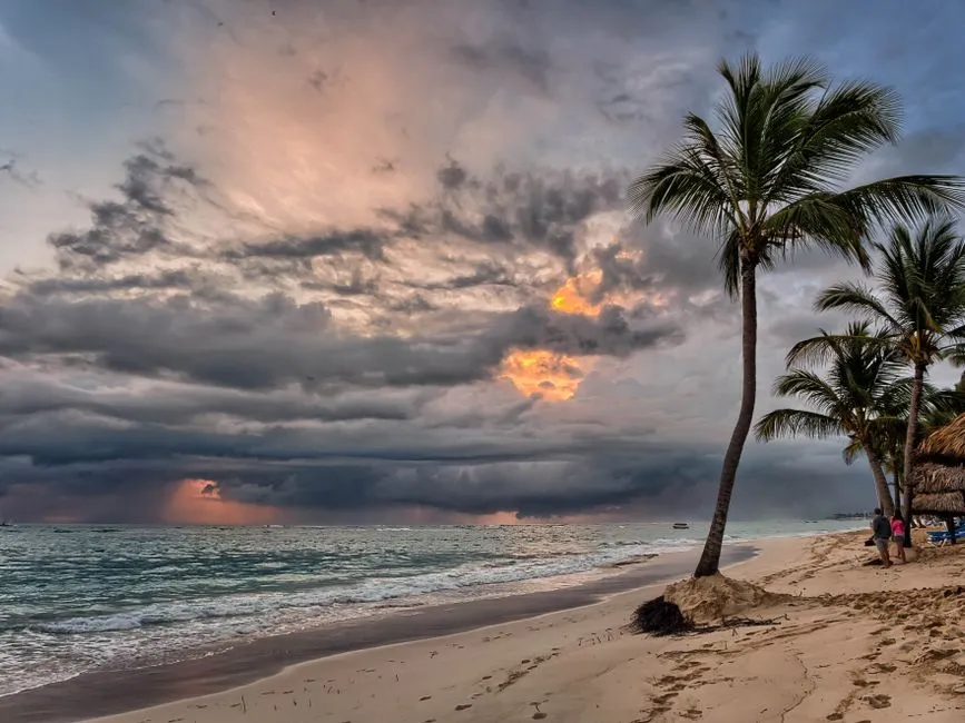 Ciel d'orage tropical chargé de nuages sombres au-dessus de la mer des Caraïbes, avec des cocotiers sur une plage pendant la saison cyclonique