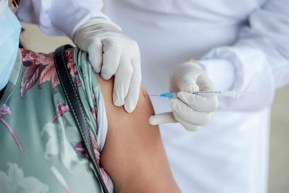 Soignant ganté injectant un vaccin dans l'épaule d'une personne avant un départ en voyage