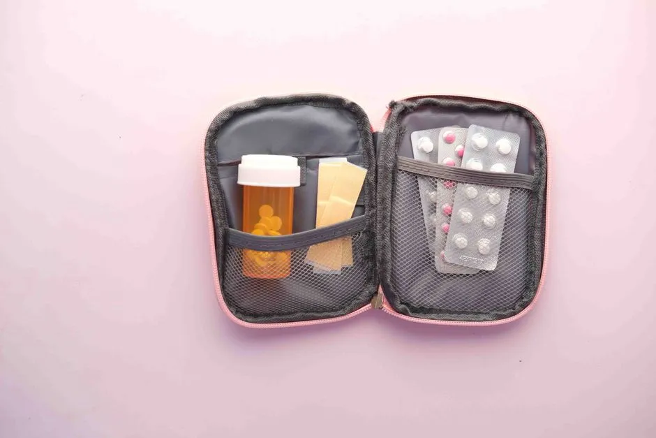 Trousse à pharmacie de voyage ouverte contenant plaquettes de comprimés, flacon de médicaments et pansements