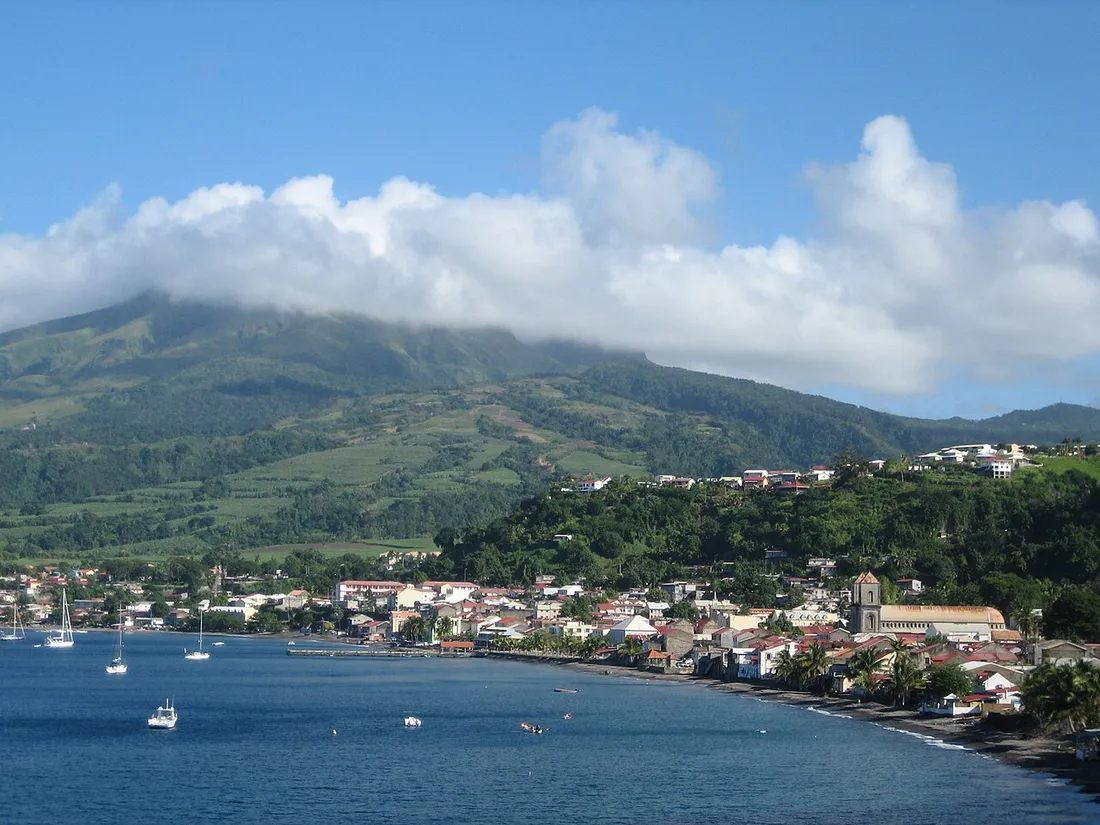 La ville de Saint-Pierre en Martinique et sa baie aux voiliers, au pied de la Montagne Pelée dont le sommet est coiffé de nuages