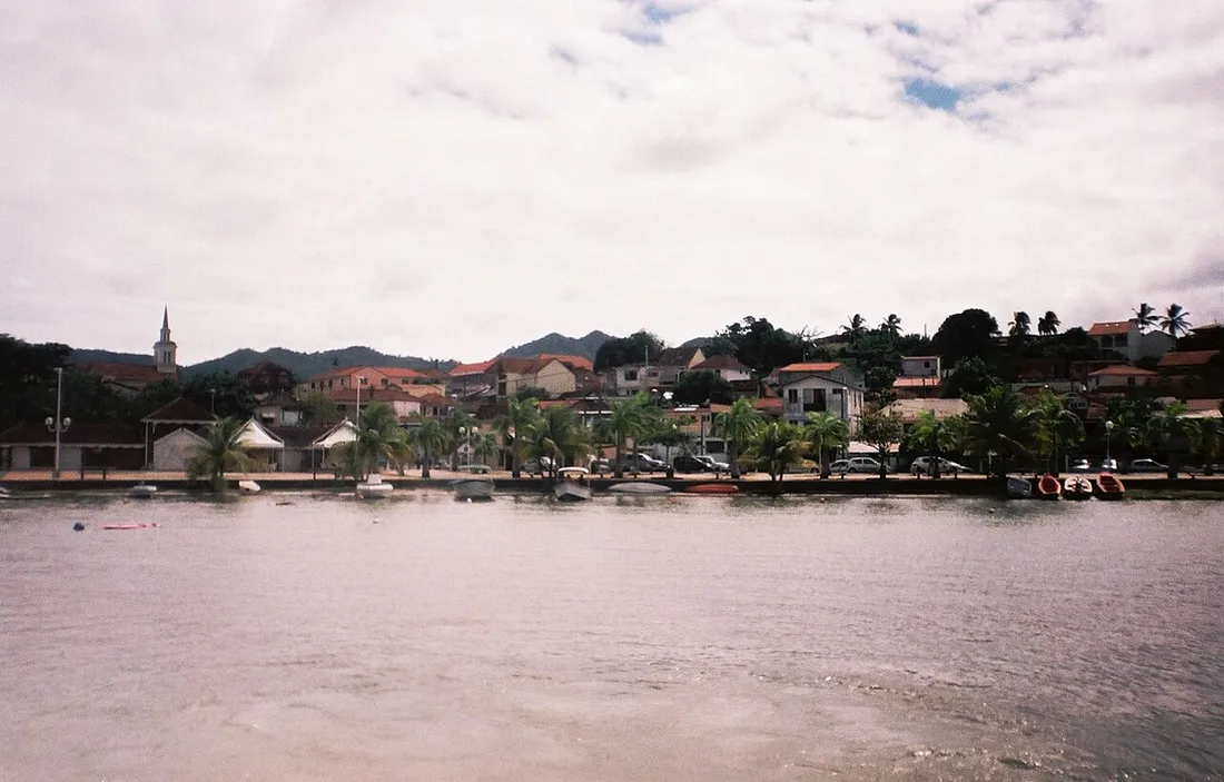 Vue du bourg des Trois-Îlets en Martinique depuis la baie, avec son clocher, ses maisons aux toits rouges et les collines en arrière-plan