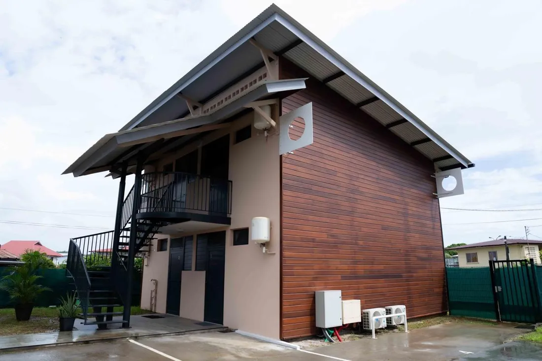 Bâtiment en bois du Baduel Smart Studio à Cayenne avec escalier extérieur et cour