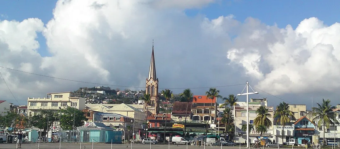 Vue de la ville de Fort-de-France en Martinique avec la flèche de la cathédrale, les toits et les palmiers sous un ciel nuageux