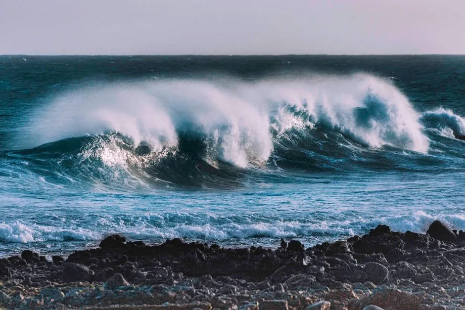 Vague de l'océan Atlantique déferlant en rouleau au-dessus d'un rivage rocheux, évoquant les spots de surf et les plages sauvages du Nord-Atlantique martiniquais