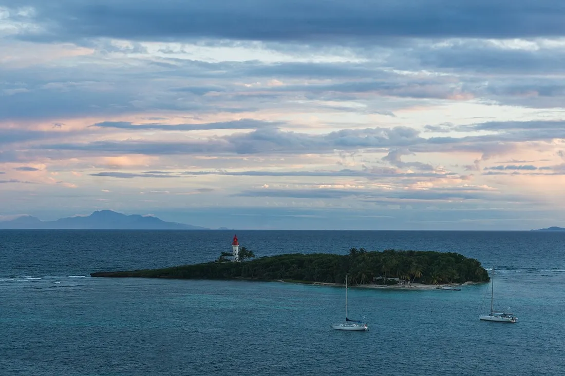 Îlet du Gosier et son phare rouge et blanc entourés de voiliers au mouillage au crépuscule, au large de la commune du Gosier en Guadeloupe