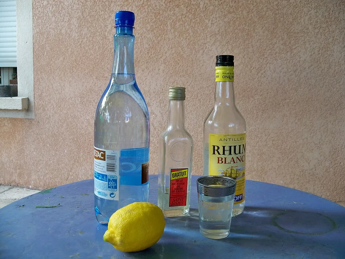 Bouteille de rhum blanc agricole des Antilles, citron vert et petit verre, ingredients de base du ti-punch