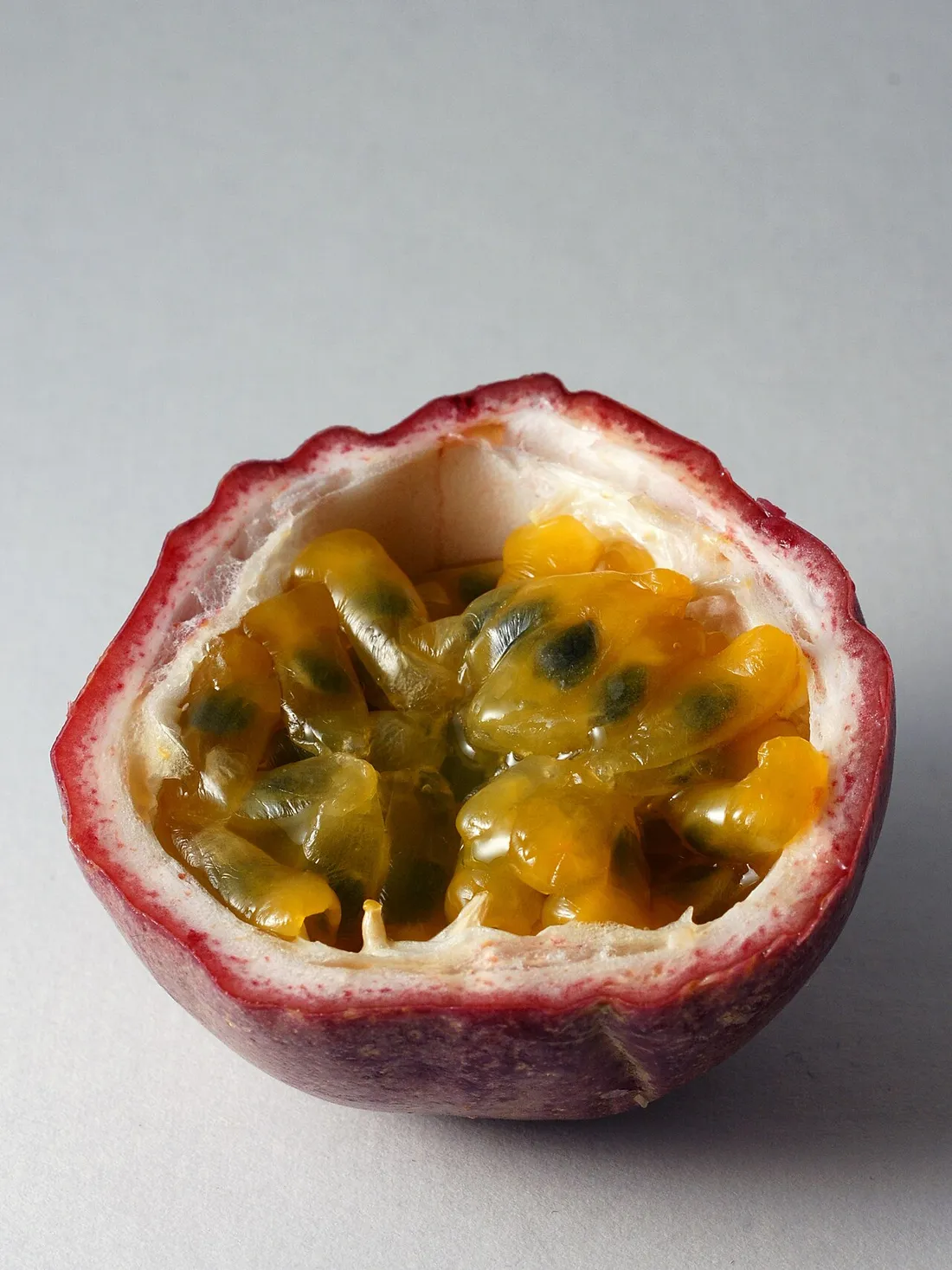 Fruit de la passion (maracuja) ouvert en deux laissant voir sa pulpe orangee et ses graines