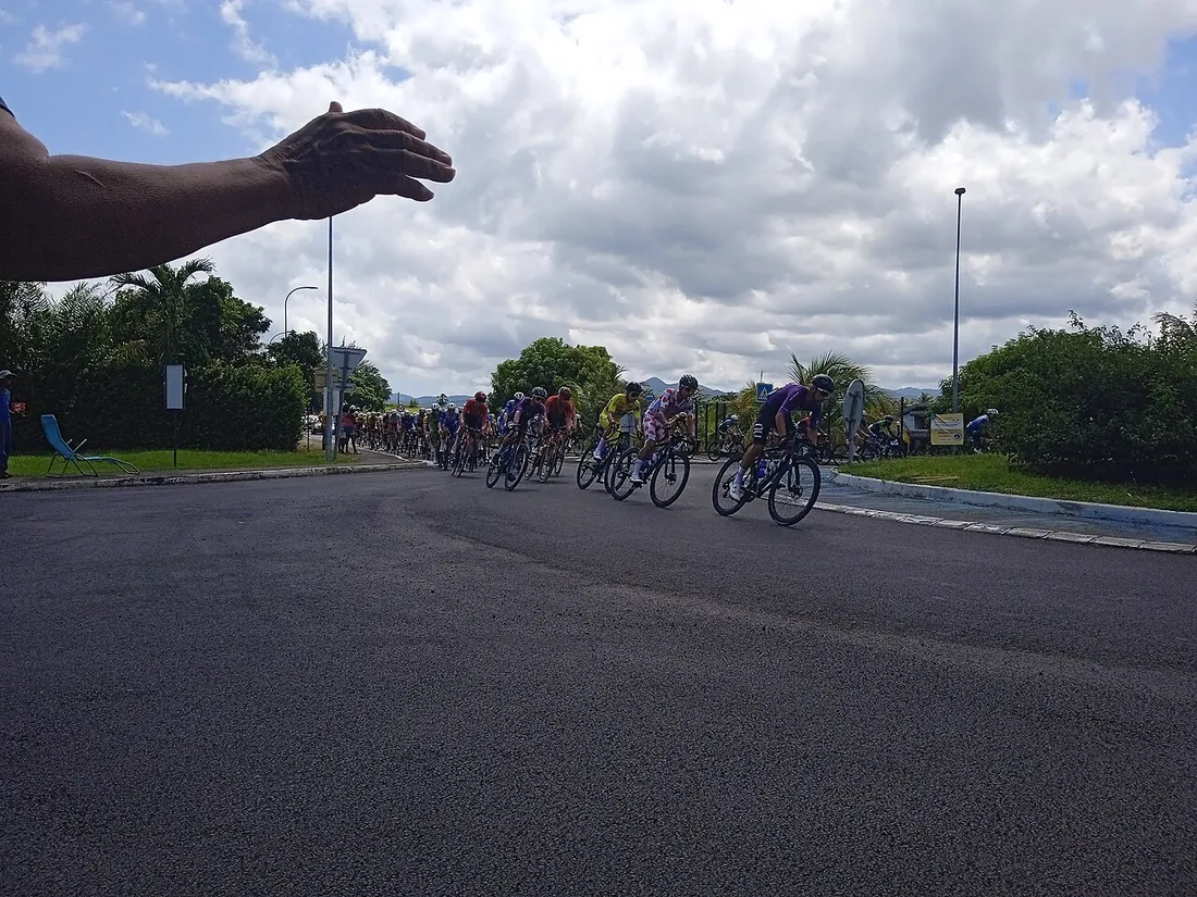 Coureurs du Tour de Guadeloupe 2025 en pleine étape à Convenance, Baie-Mahault, encouragés par un spectateur au bord de la route