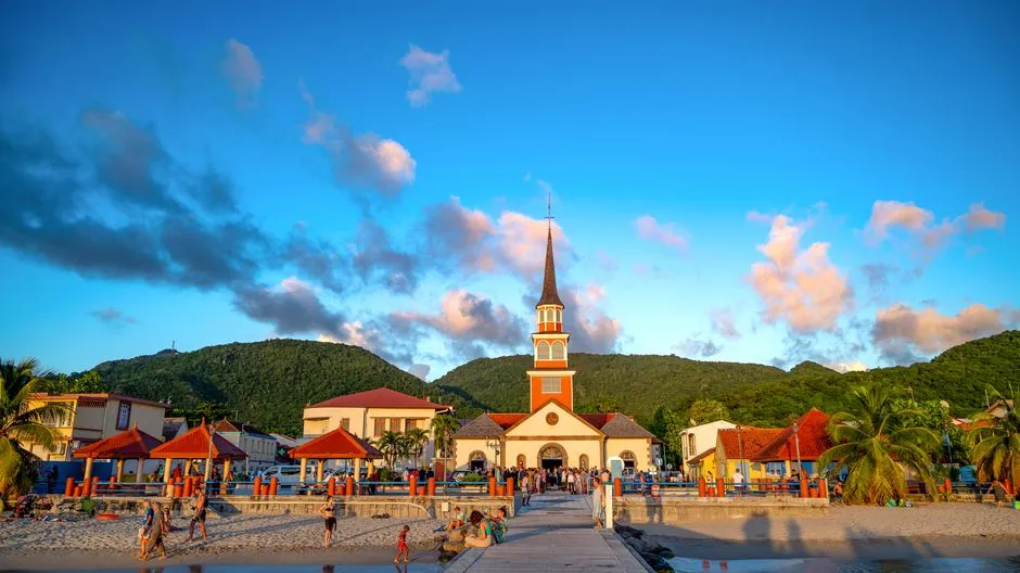 Église de bord de mer et village de Martinique illuminés par la lumière dorée du coucher de soleil