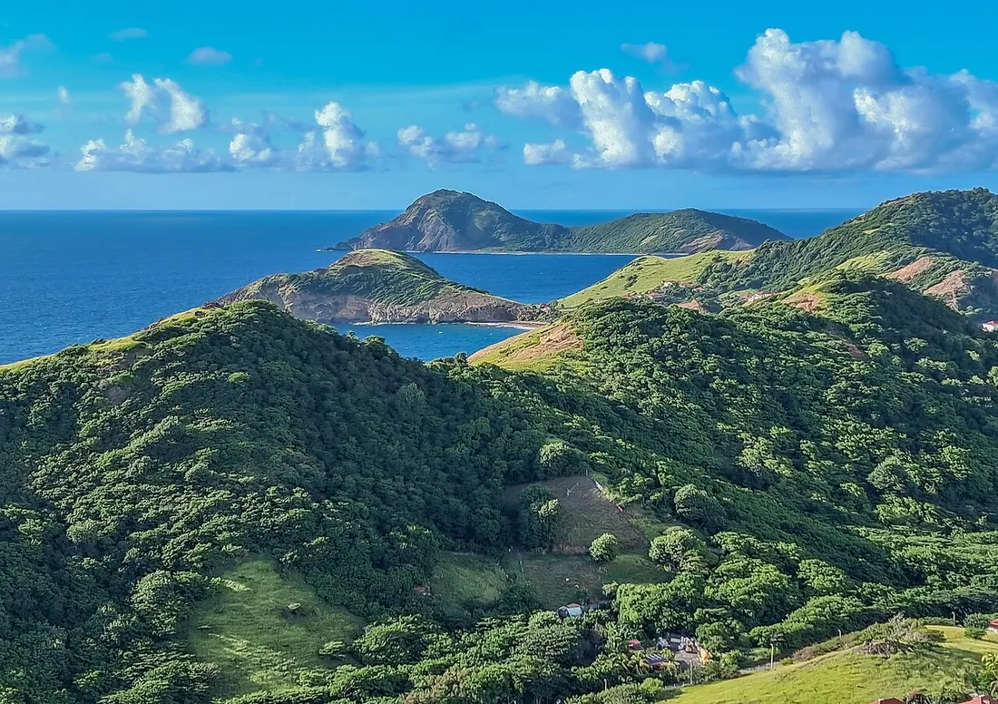 Crêtes verdoyantes de Terre-de-Haut aux Saintes descendant vers une anse cachée et la mer des Caraïbes