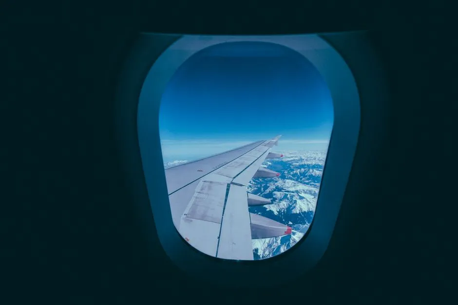 Vue depuis le hublot d'un avion en vol, aile au-dessus des nuages, illustrant un trajet aerien vers la Guadeloupe