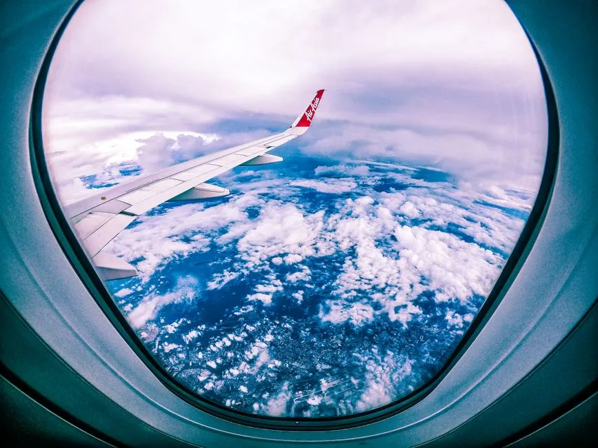 Vue par le hublot d'un avion de ligne en vol, aile et winglet au-dessus des nuages